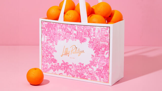 Shopping bag with logo on side and oranges spilling out